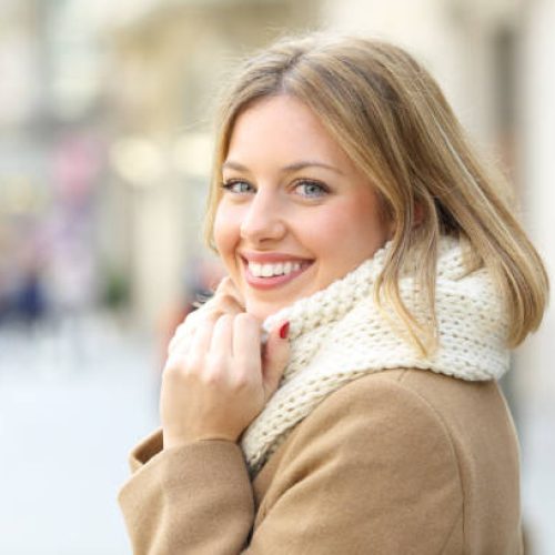 Portrait of a happy woman posing looking at camera in winter in the street